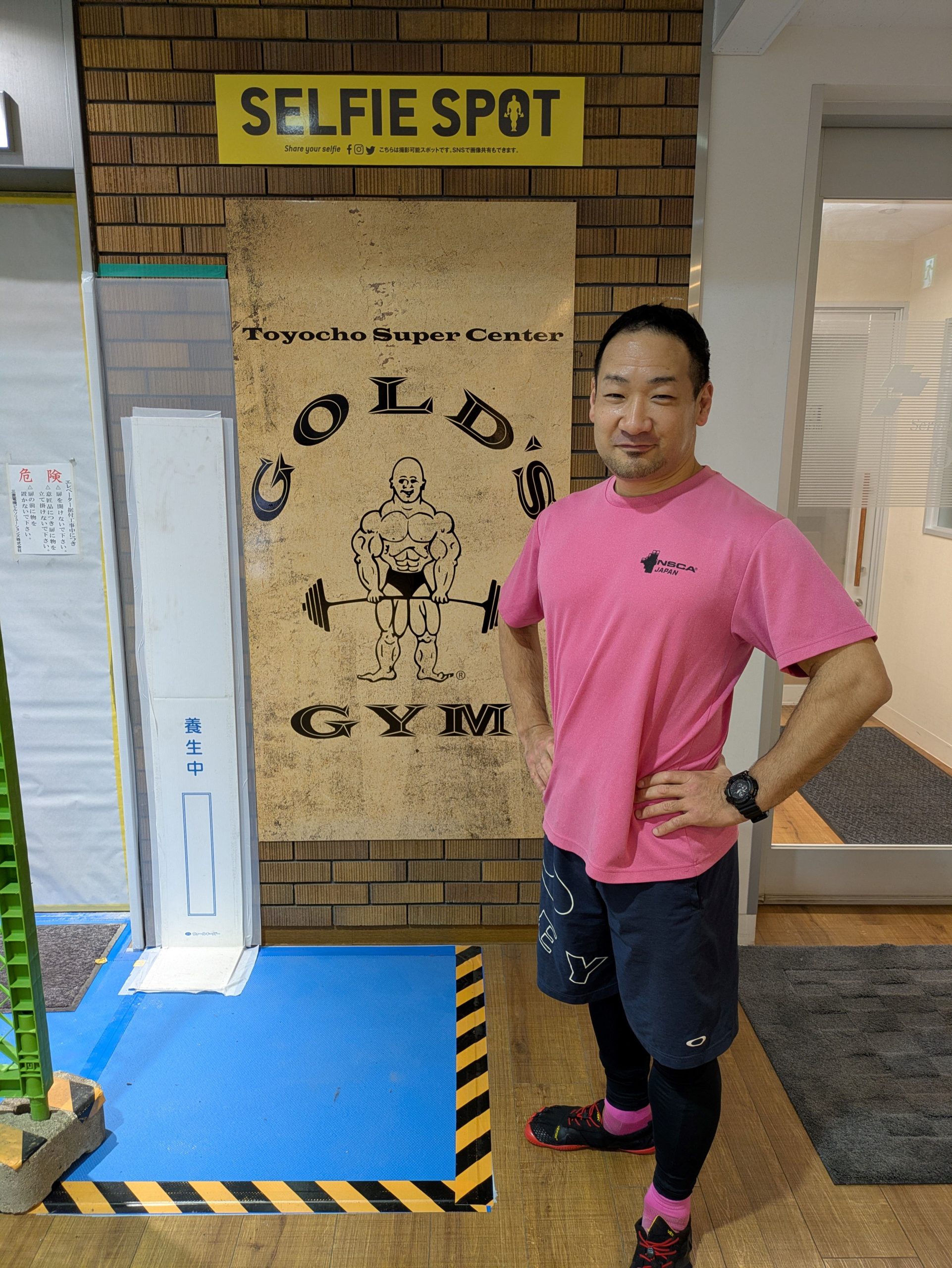 ピンクシャツデーに参加する株式会社肉体改造研究所・竹田大介。NSCAジャパンのピンクTシャツを着用し、ゴールドジム東陽町スーパーセンターにて撮影。